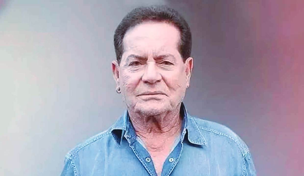 Salim Khan in a recent portrait photo, wearing a denim shirt and looking serious, used in news coverage about his hospitalization.